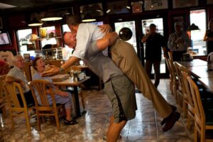 President Obama is lifted in the air by Scott Van Duzer, owner of the Big Apple Pizza owner.