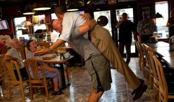 President Obama is lifted in the air by Scott Van Duzer, owner of the Big Apple Pizza owner.